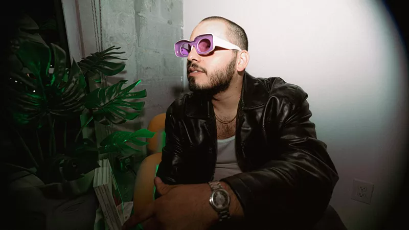 Image: man posing with pink and white sunglasses and a black jacket