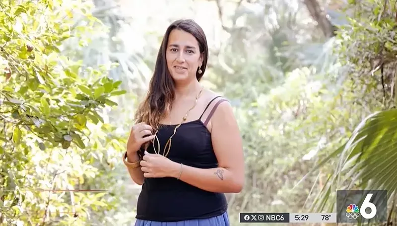 Image: Andrea Dos Passos in a black tank-top standing in front of trees