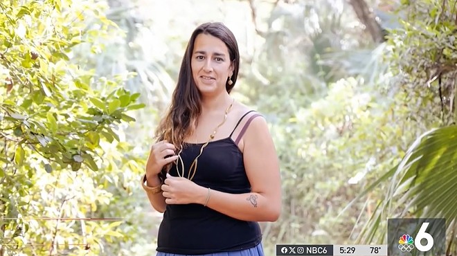 Andrea Dos Passos in a black tank-top standing in front of trees