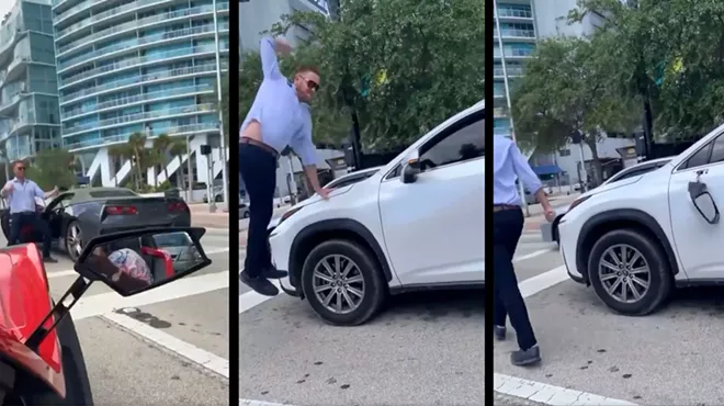 An enraged man leaps into the air in downtown traffic to deliver a hammer fist to an SUV's driver-side mirror
