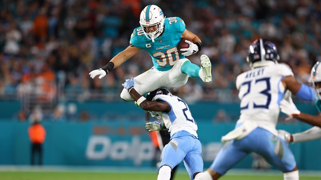 Miami Dolphins player jumping over a defender.