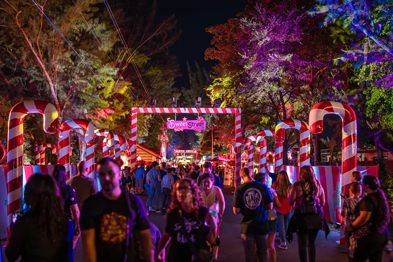 Image: People walking around Sweet Street at Christmas Wonderland. Life-size candy canes stand on both sides of the walkway,