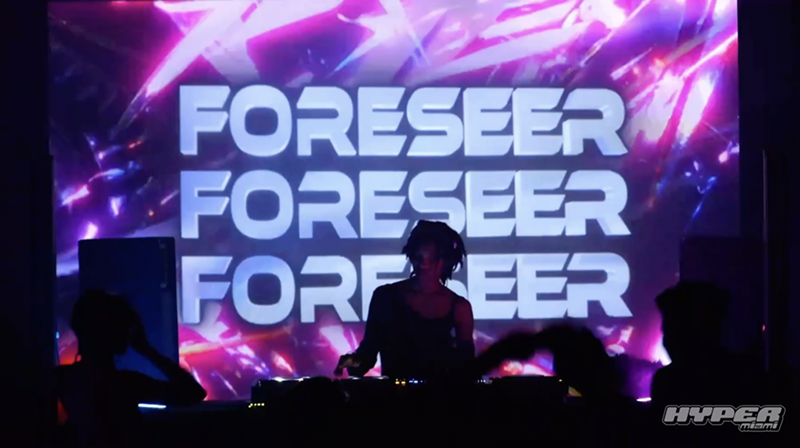 Image: DJ is playing in front of an LED screen.