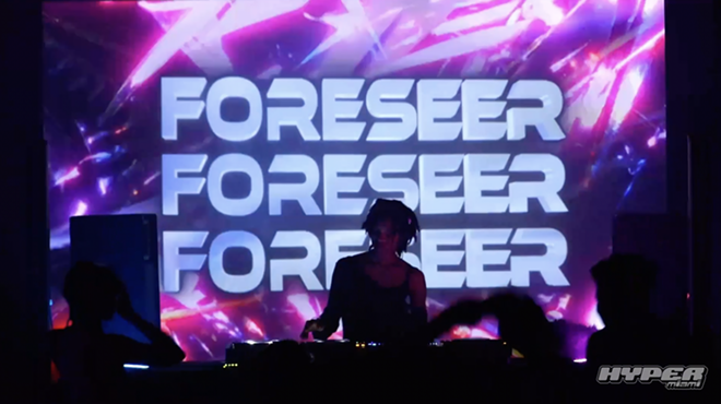 DJ is playing in front of an LED screen.