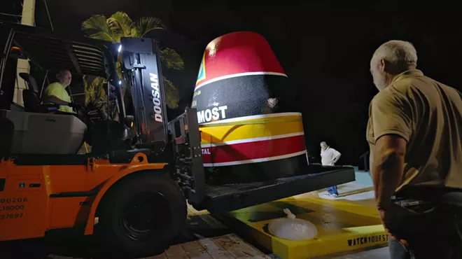 A tractor picks up a painted concrete buoy