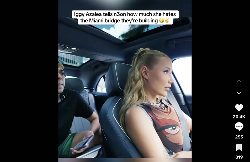 Image: Screenshot of a TikTok video showing livestreamer N3on in the back of a car being driven by rapper Iggy Azalea. Text overlayed over the image reads, "Iggy Azalea tells N3on how much she hates the Miami bridge they're building 🤣✌️"