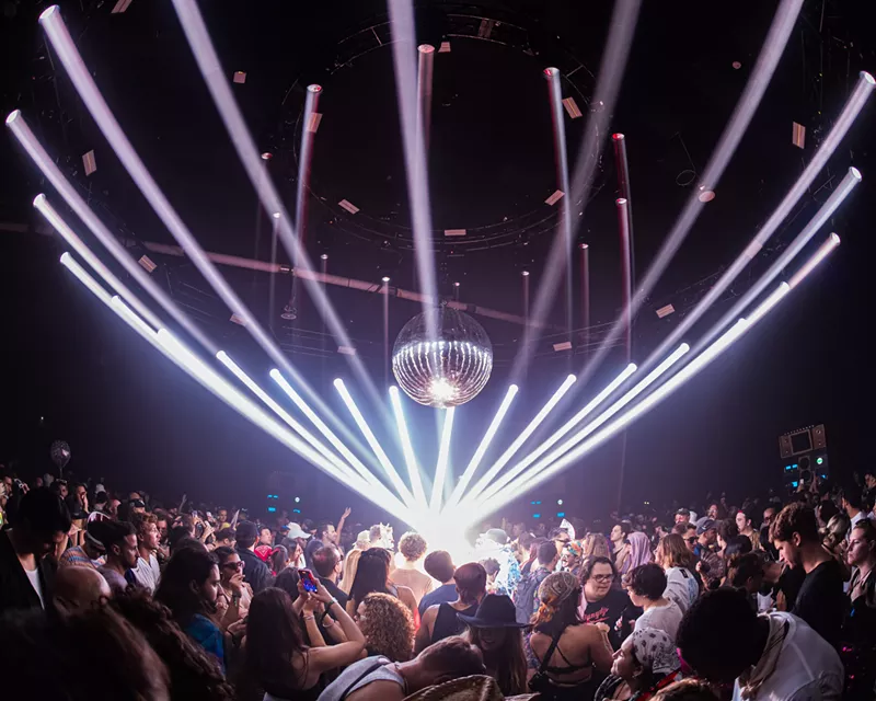 Image: dancers dance on a dance floor underneath a disco ball