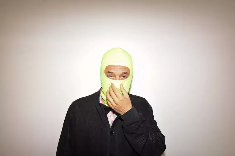 Image: Harmony Korine, with his face covered by a neon-green balaclava
