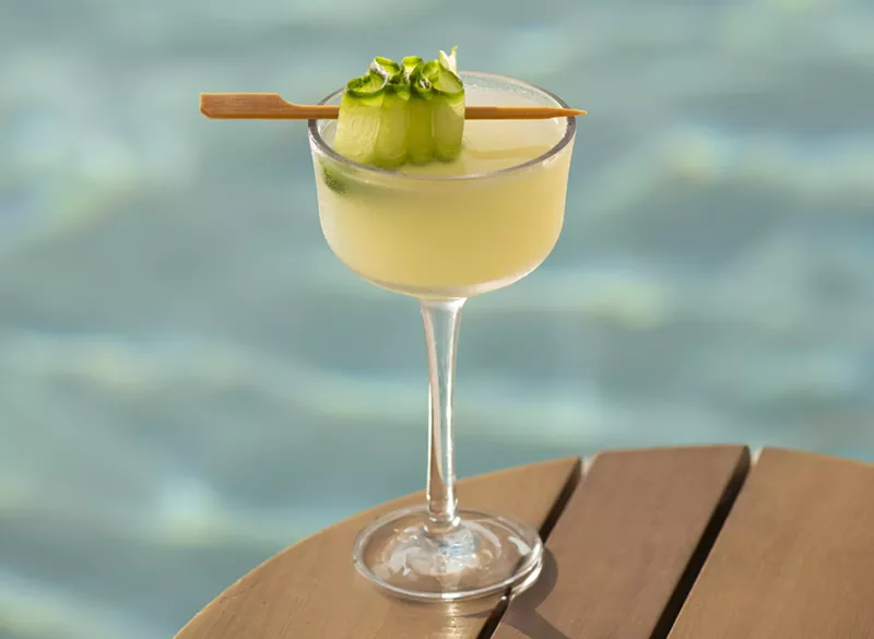 Image: A yellow cocktail with a pool in the background