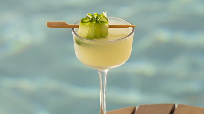 A yellow cocktail with a pool in the background