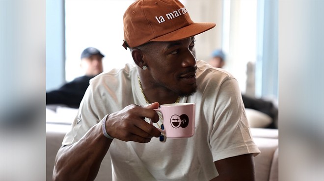 Basketball star Jimmy Butler wearing a ballcap and drinking coffee out of a Bigface branded mug