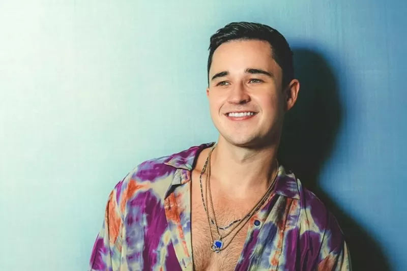 Image: DJ and producer John Summit standing against a blue background
