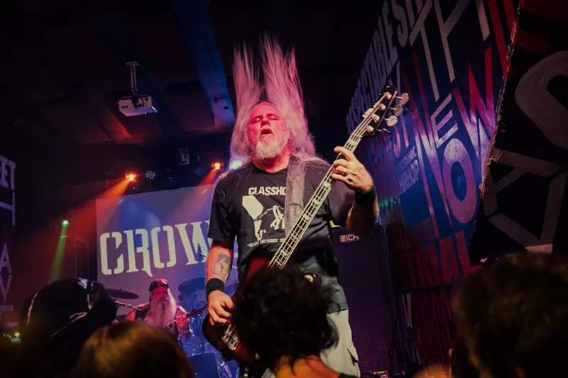 Image: Bass player of a metal band performing in front of a crowd.