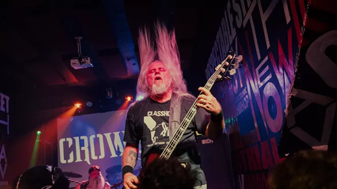 Bass player of a metal band performing in front of a crowd.