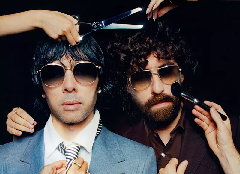 Image: Two men are putting on makeup and getting a haircut