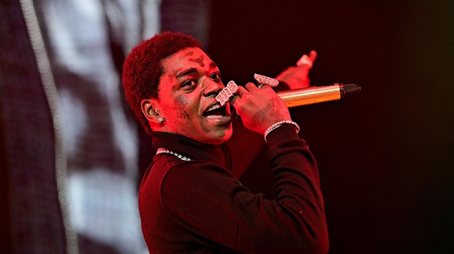Rapper Kodak Black raps into a microphone on stage