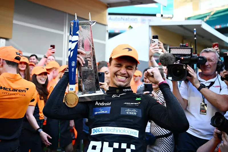 Image: Lando Norris holding his trophy surrounded by reporters