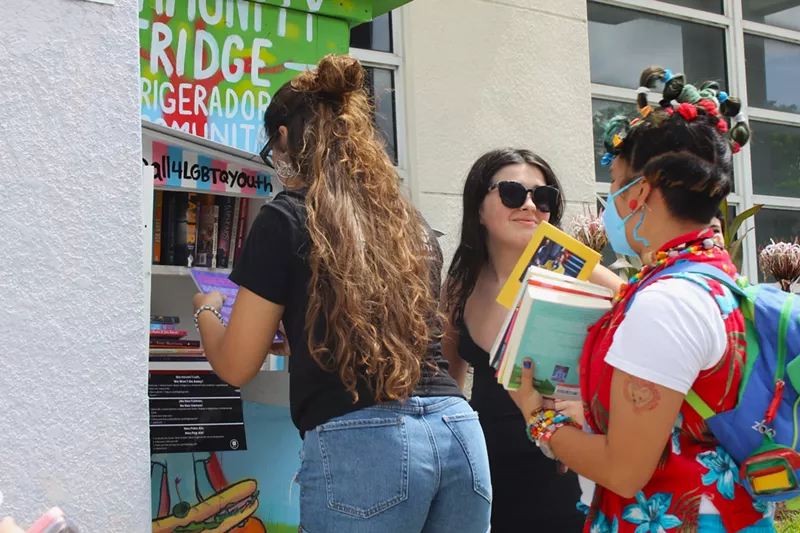 Image: Nadya, Lucia Nuno, and Vince Cuadra (left to right) fill the first Little Library with books at the Allapattah YMCA on July 15, 2023.