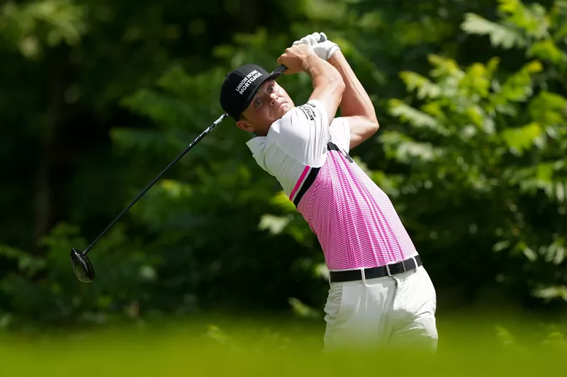Image: Luke Clanton on the back end of a golf swing, his eyes wide and his face tense