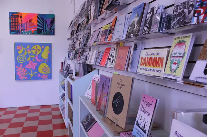 Image: Wall of colorful zines, books, and prints lined up for sale beside bright checkerboard tiles at Dale Zine.
