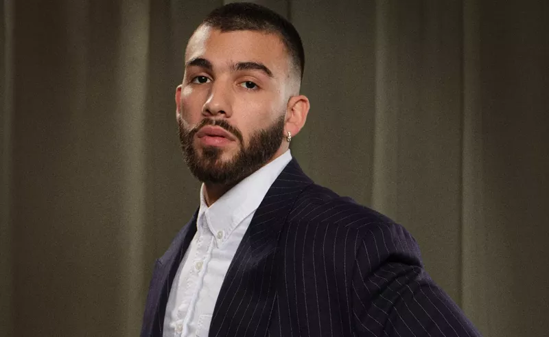 Image: headshot of Manuel Turizo wearing a dress shirt and blazer