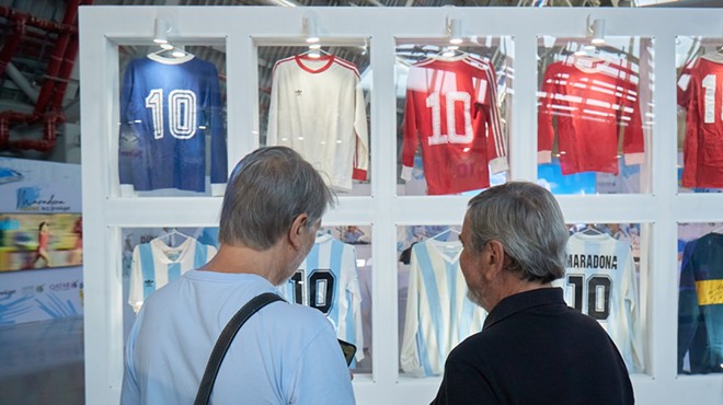 Two men looking at a display of Diego Maradona's soccer jerseys