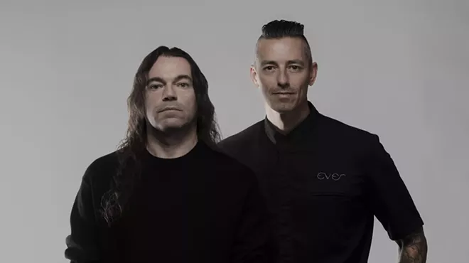 Two men posing for the camera wearing black.