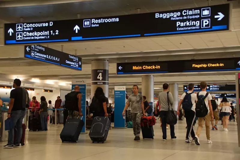 Image: A photo of passengers with luggage inside Miami International Airport.