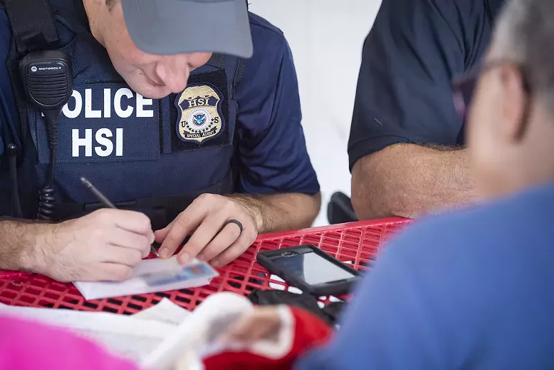 Image: U.S. Immigration and Customs Enforcement officers sit across from a man