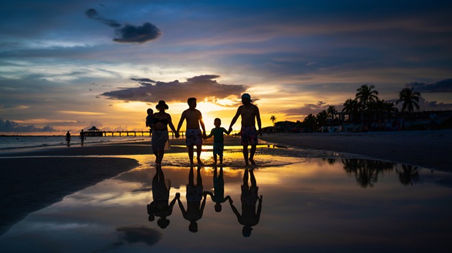 A silhouette of a family walking on a beach at sunset