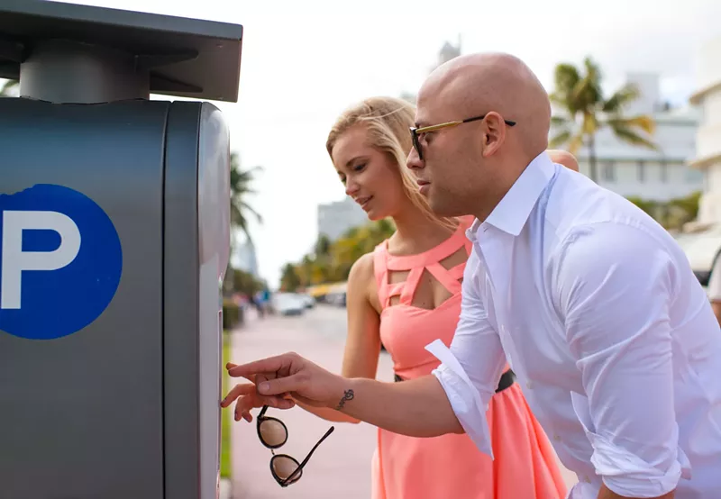 Image: A woman and a man pay at a Pay by Phone meter in Miami Beach