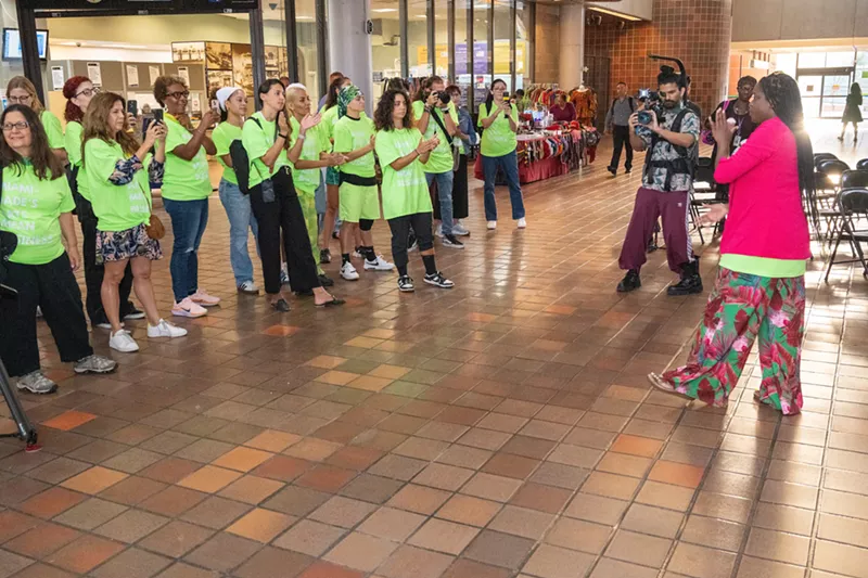 Image: protesters in lime-green t-shirts gather at a train station