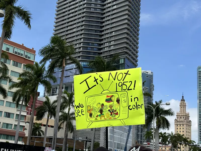 Image: A sign at a protest states, "It's not 1952. We see in color."