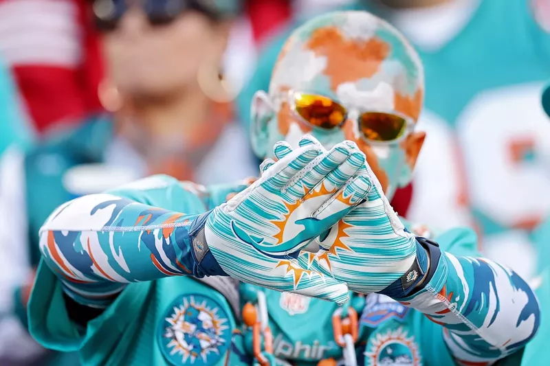 Image: NFL football fan decked out in Miami Dolphins regalia, right down to his gloves and painted bald head