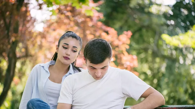 A woman looking over a man's shoulder at his phone