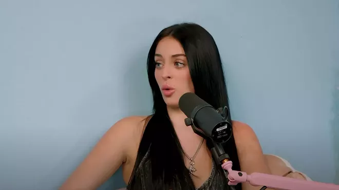a woman sits in front of a microphone to record a podcast