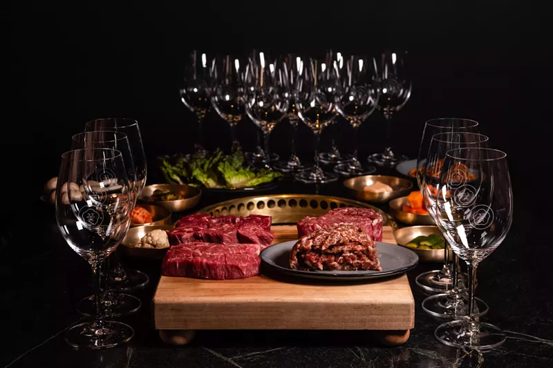 Image: Raw steaks on a cutting board surrounded by empty wine glasses