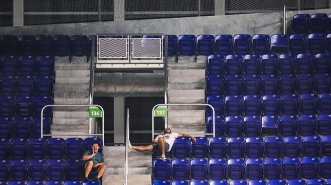 Two fans at the Miami Marlins' stadium in a sea of empty seats