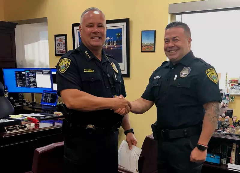 Image: two uniformed police officers shake hands and smile at the camera