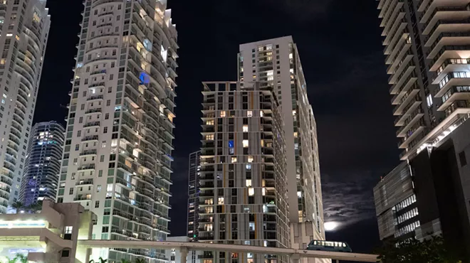 Brickell skyline by night with Metromover crossing bridge in the foreground