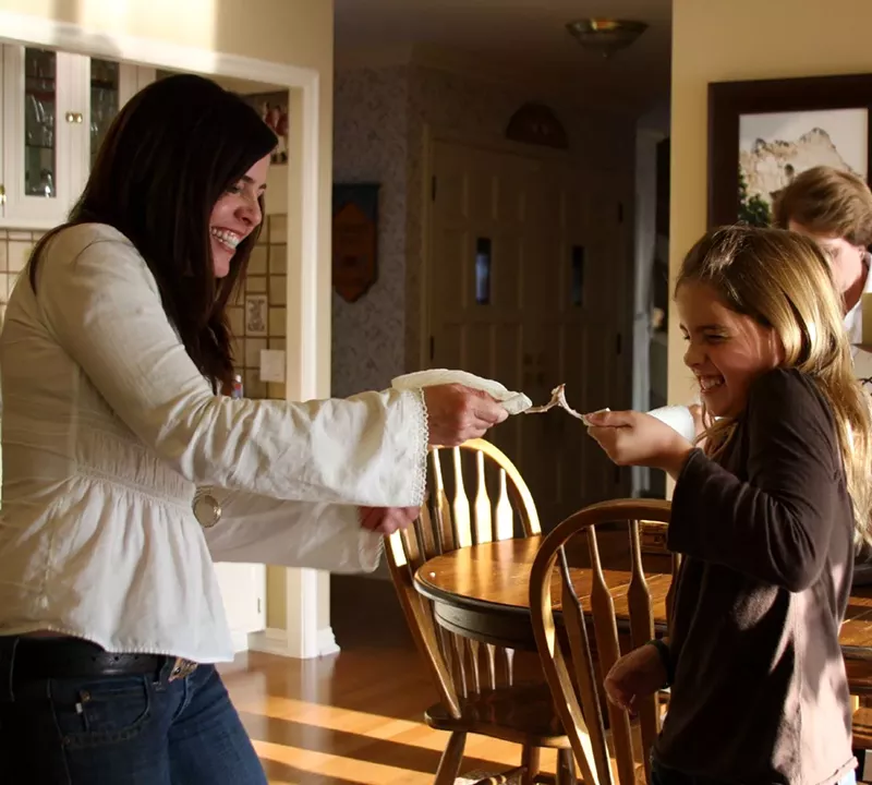Image: Two people smiling while pulling apart a wishbone, engaging in the traditional wishbone-breaking ritual for good luck