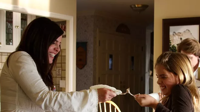 Two people smiling while pulling apart a wishbone, engaging in the traditional wishbone-breaking ritual for good luck