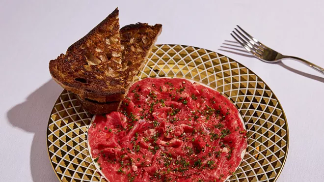 steak tartare in a ceramic serving dish with a side of toasted bread