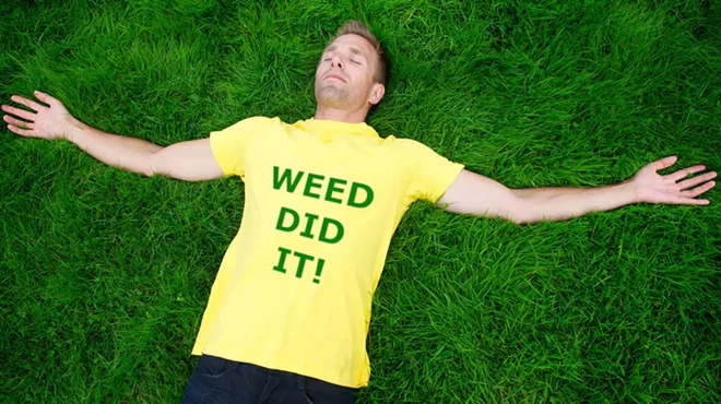 Man laying on grace with yellow shirt that reads,"Weed did it!"