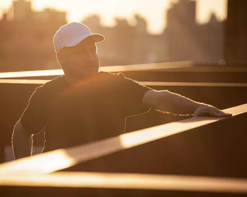 Image: DJ Danny Tenaglia stands on a rooftop, basking in the sunlight