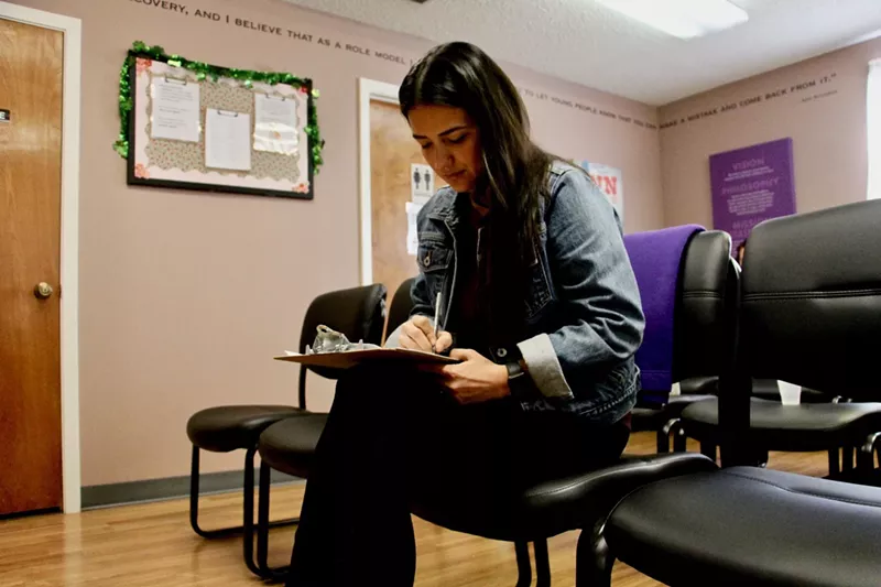 Image: woman in the waiting room of a health clinic, filling out a form
