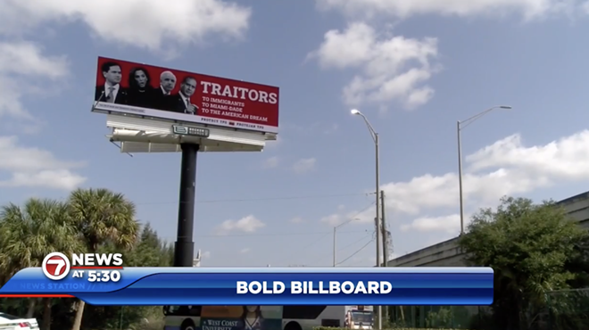 A photo of a red billboard with four politicians on it and the words: “TRAITORS: To Immigrants, To Miami-Dade, To The American Dream” above a blue sky