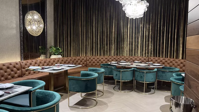 Image: Plush teal seats fill the cozy interior dining area of Baires Grill in Downtown Doral