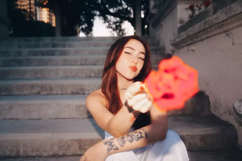 Image: Nicki Nicole holding a flower toward the camera