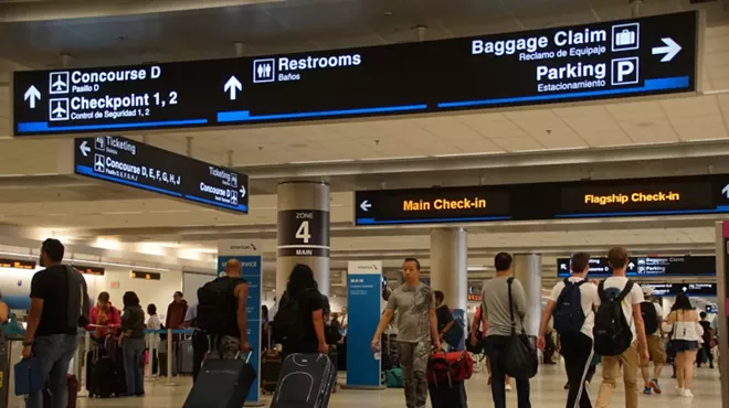A photo of passengers with luggage inside Miami International Airport.